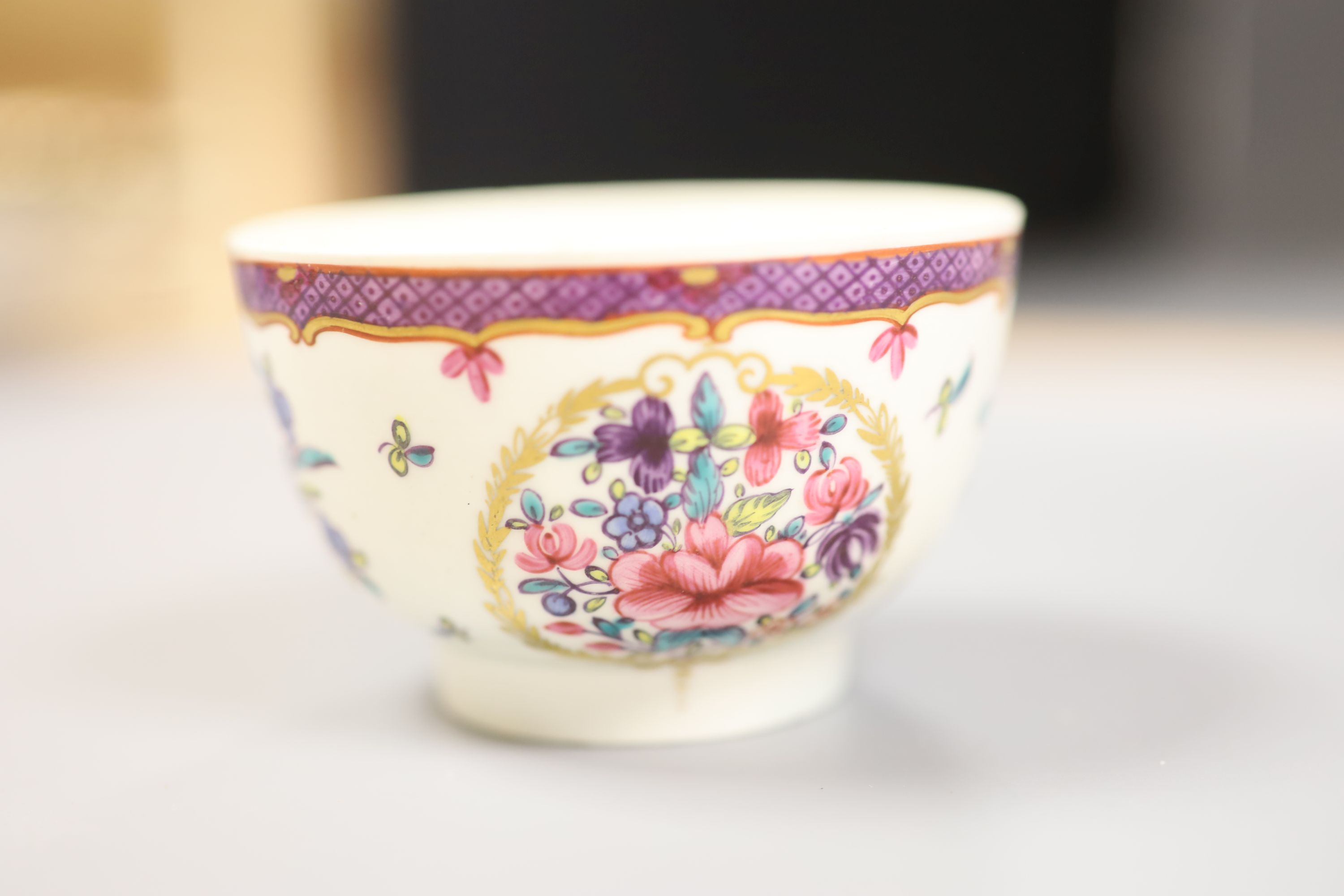 An 18th century Worcester teabowl and saucer painted Companie des Indes style with flowers in a circular gilt leaf panel